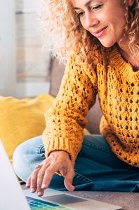 woman with yellow cardigan using laptop