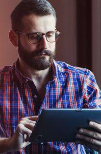 man wearing glasses using tablet