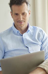 man with blue shirt using laptop